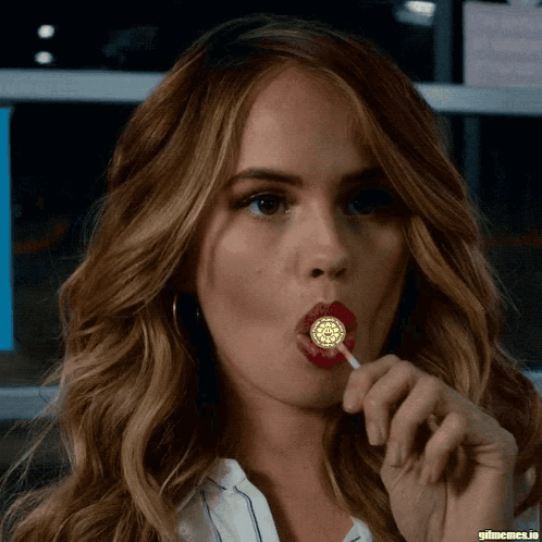 A Close Up Of A Woman Licking A Lollipop With Gifmemes.io In The Corner GIF