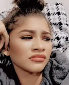A Close Up Of A Woman Making A Funny Face While Sitting In Bed . GIF