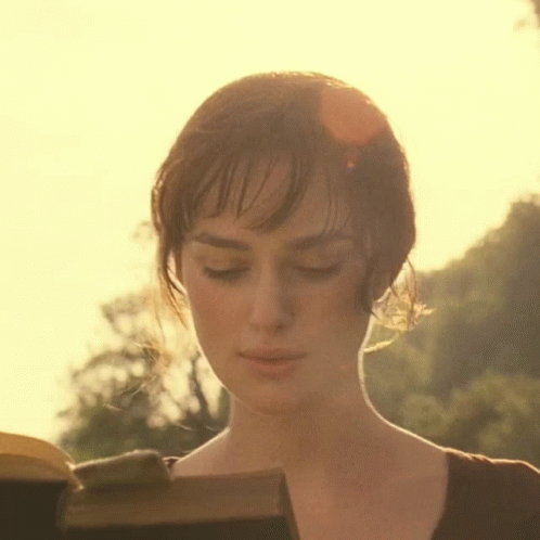 A Close Up Of A Woman Reading A Book With The Sun Shining Through Her Hair GIF