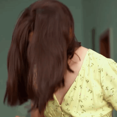 A Close Up Of A Woman 'S Back With Her Hair Blowing In The Wind GIF