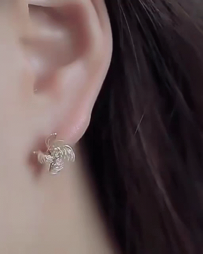 A Close Up Of A Woman 'S Ear Wearing A Pair Of Earrings . GIF