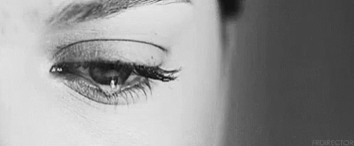 A Close Up Of A Woman 'S Eye With A Tear Running Down It . GIF