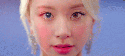 A Close Up Of A Woman 'S Eye With Glitter On It And A Red Background . GIF