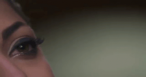 A Close Up Of A Woman 'S Eye With Long Eyelashes And A Green Background . GIF