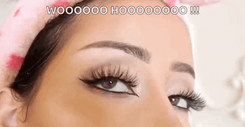 A Close Up Of A Woman 'S Eye With Long Eyelashes And A Pink Headband On Her Head . GIF