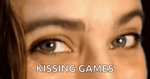 A Close Up Of A Woman 'S Eyes With The Words `` Kissing Games '' Written Above Them . GIF
