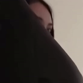 A Close Up Of A Woman 'S Face Behind A Black Curtain . GIF