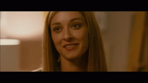 A Close Up Of A Woman 'S Face In A Dark Room Smiling . GIF