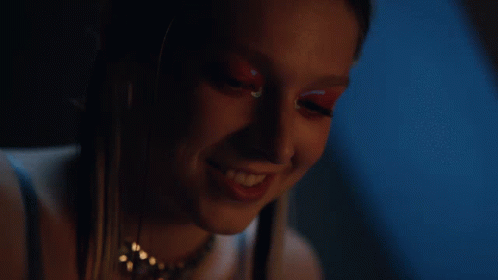 A Close Up Of A Woman 'S Face In A Dark Room With A Blue Background GIF