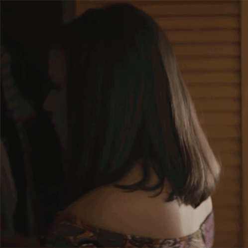 A Close Up Of A Woman 'S Face In A Dark Room With A Lamp In The Background . GIF