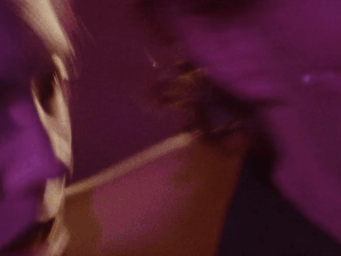 A Close Up Of A Woman 'S Face In A Purple Light GIF