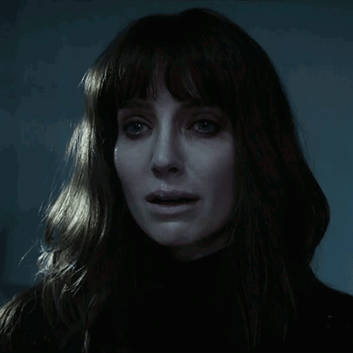 A Close Up Of A Woman 'S Face In The Dark GIF