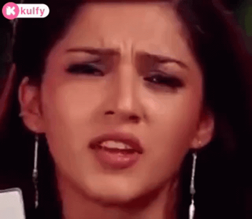 A Close Up Of A Woman 'S Face Making A Funny Face While Holding A Cell Phone . GIF