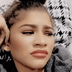 A Close Up Of A Woman 'S Face Making A Funny Face While Sitting On A Bed . GIF