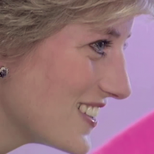 A Close Up Of A Woman 'S Face Smiling And Wearing Earrings GIF