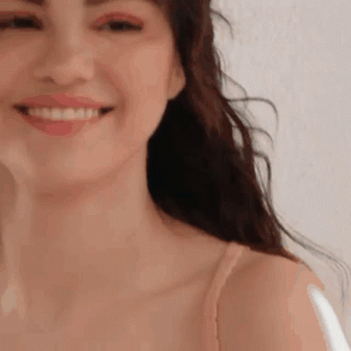 A Close Up Of A Woman 'S Face Smiling While Wearing A Bra . GIF