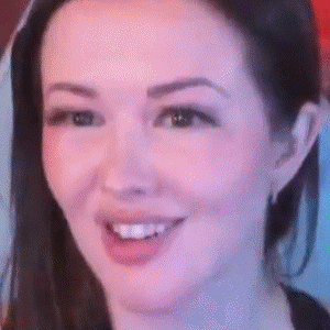 A Close Up Of A Woman 'S Face Smiling With A Purple Background . GIF
