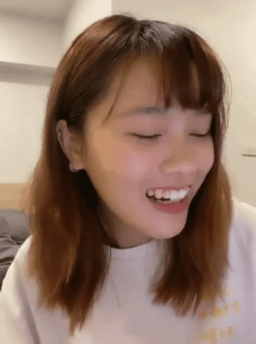 A Close Up Of A Woman 'S Face Smiling With Her Eyes Closed . GIF