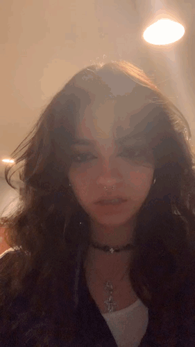 A Close Up Of A Woman 'S Face Wearing A Choker Necklace And Earrings GIF