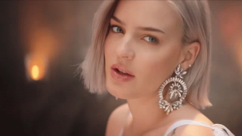 A Close Up Of A Woman 'S Face Wearing A Pair Of Earrings GIF