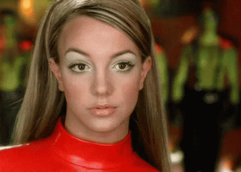 A Close Up Of A Woman 'S Face Wearing A Red Turtleneck Sweater . GIF