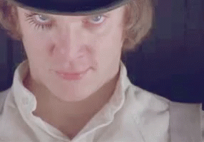 A Close Up Of A Woman 'S Face Wearing A Top Hat And Suspenders . GIF
