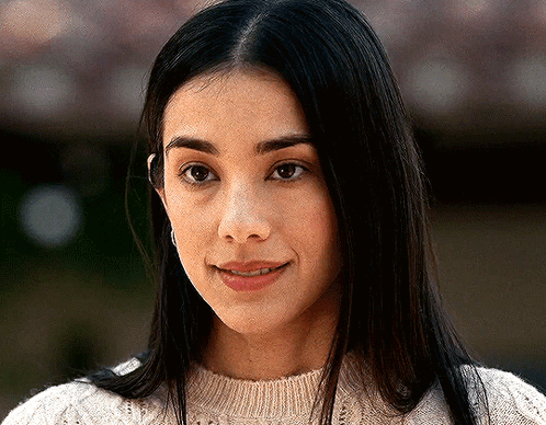 A Close Up Of A Woman 'S Face Wearing A White Sweater And Smiling . GIF