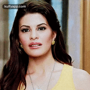 A Close Up Of A Woman 'S Face Wearing A Yellow Top And Earrings . GIF