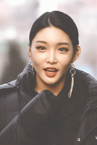 A Close Up Of A Woman 'S Face Wearing Earrings And A Black Jacket GIF
