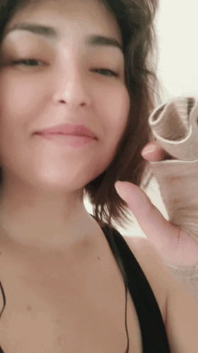 A Close Up Of A Woman 'S Face While Holding A Piece Of Paper GIF