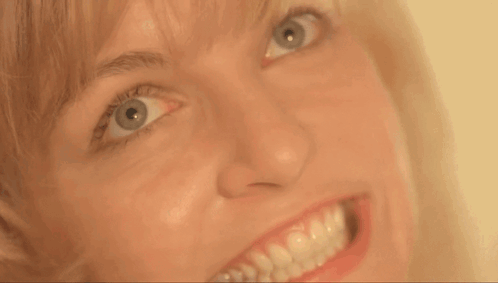 A Close Up Of A Woman 'S Face With A Big Smile GIF