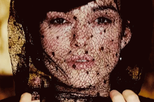 A Close Up Of A Woman 'S Face With A Black Lace Veil GIF