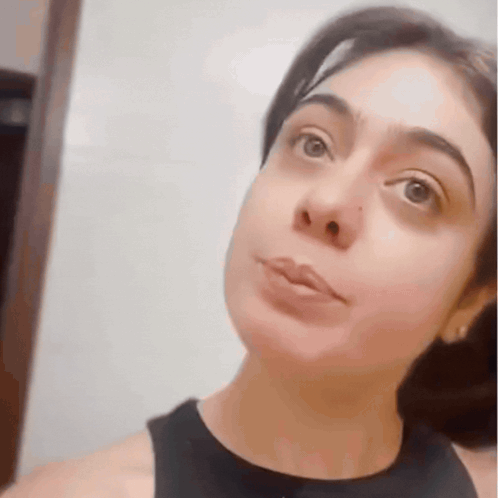 a close up of a woman 's face with a black tank top