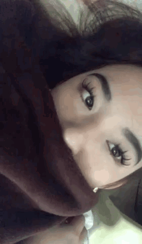 A Close Up Of A Woman 'S Face With A Blanket Covering Her Mouth . GIF