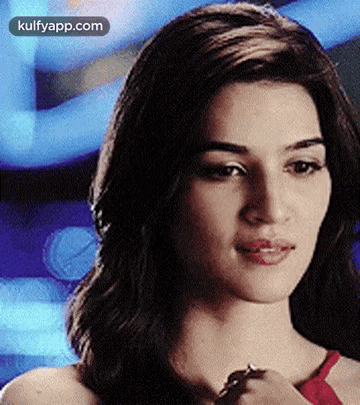 A Close Up Of A Woman 'S Face With A Blue Background And A Ring On Her Finger . GIF