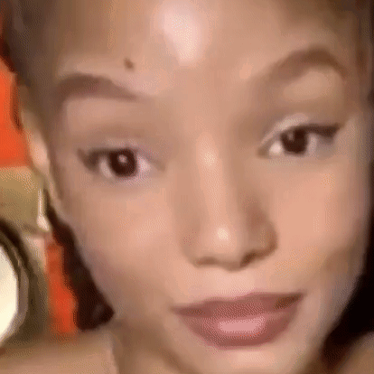 A Close Up Of A Woman 'S Face With A Blurred Background Looking At The Camera . GIF