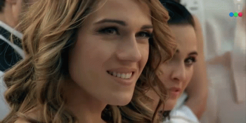 A Close Up Of A Woman 'S Face With A Blurred Image Of A Man In A Suit Behind Her GIF