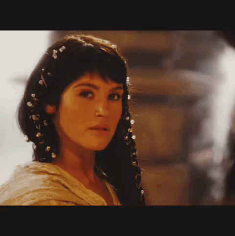 A Close Up Of A Woman 'S Face With A Braid And Pearls In Her Hair GIF