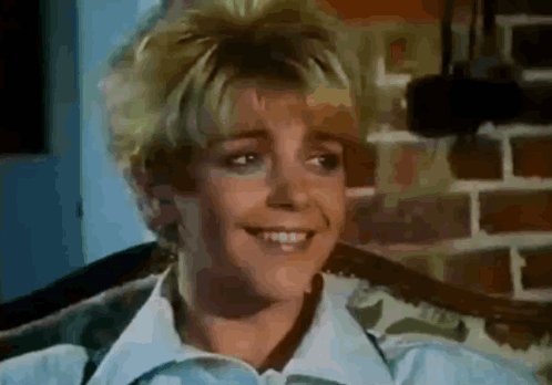 A Close Up Of A Woman 'S Face With A Brick Wall In The Background GIF