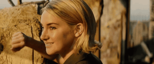 A Close Up Of A Woman 'S Face With A Brick Wall In The Background . GIF
