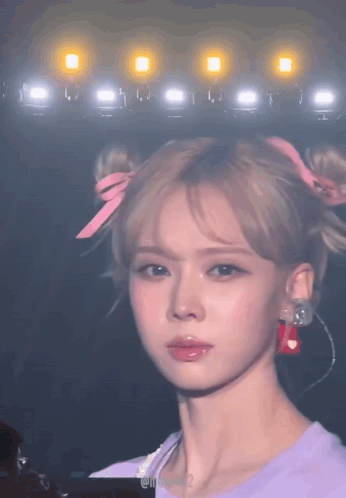 A Close Up Of A Woman 'S Face With A Bun And Earrings GIF