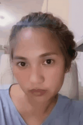 A Close Up Of A Woman 'S Face With A Bun On Her Head . GIF