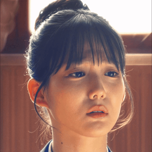 A Close Up Of A Woman 'S Face With A Bun On Her Head GIF