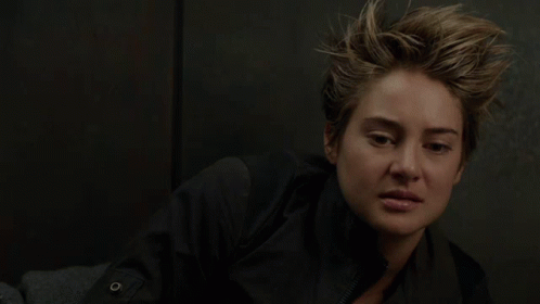 A Close Up Of A Woman 'S Face With A Button On Her Jacket GIF