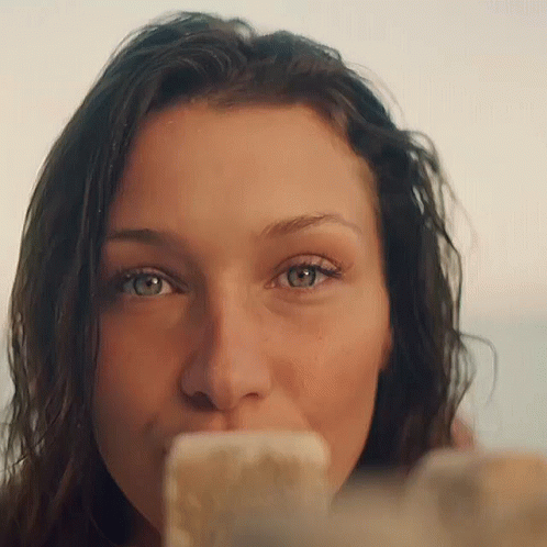 A Close Up Of A Woman 'S Face With A Cell Phone In Her Mouth GIF