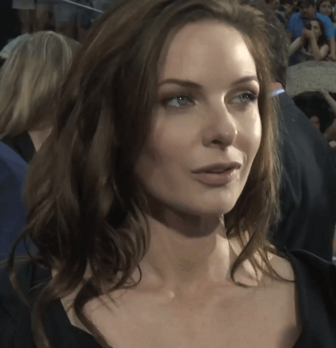 a close up of a woman 's face with a crowd of people behind her