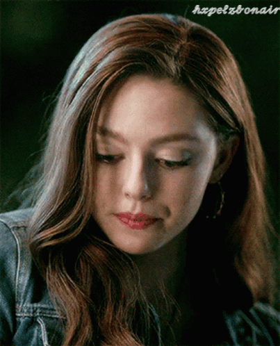 A Close Up Of A Woman 'S Face With A Denim Jacket And Earrings . GIF
