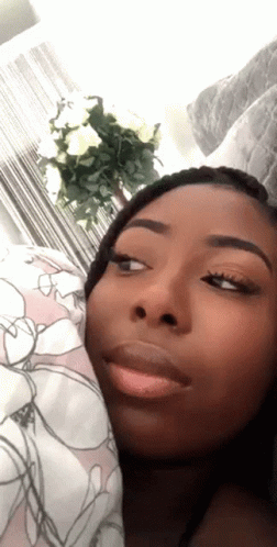 A Close Up Of A Woman 'S Face With A Floral Blanket In The Background GIF