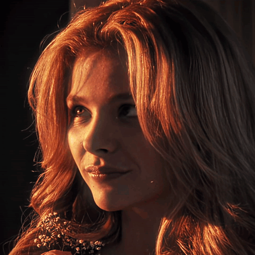 A Close Up Of A Woman 'S Face With A Flower In Her Hair GIF