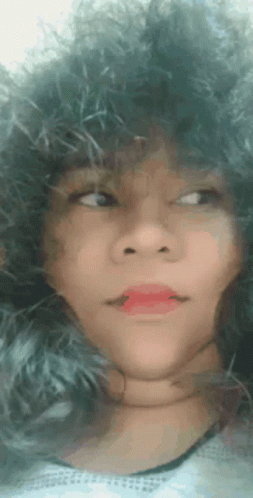 a close up of a woman 's face with a furry hat and red lipstick .